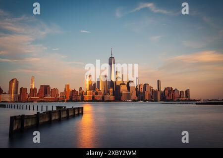 Lange Sicht der Skyline von Manhattan aus Hoboken, New Jersey, in der Abenddämmerung. Das ruhige Abendlicht unterstreicht die berühmten Wolkenkratzer der Stadt Stockfoto