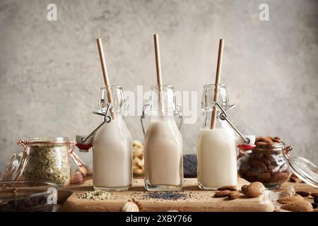 Vegane Nussmilch aus Hanfmohn und Mandeln in drei Glasflaschen mit recycelbaren Papierhalmen Stockfoto