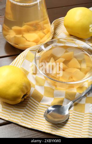 Köstliches Quittengetränk, frisches Obst und Löffel auf Holztisch Stockfoto