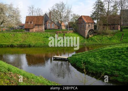 Malerisches Ufer mit traditionellen Bauernhäusern und einer Windmühle, umgeben von Bäumen und Grasland in einer ruhigen Umgebung, Vreden, Norden Stockfoto