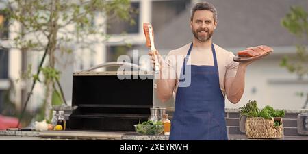 Foto von gegrilltem Lachsfisch auf der man Wear Kochschürze, Werbung. Stockfoto