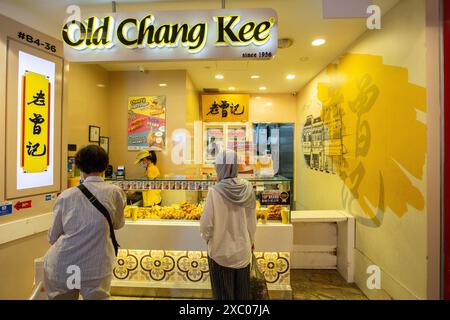 Old Chang Kee ist Halal-Zertifizierung von Majlis Ugama Islam Singapura Outlet, Eine muslimische Dame kann gesehen werden, die sich um warme Snacks schlange. Singapur. Stockfoto