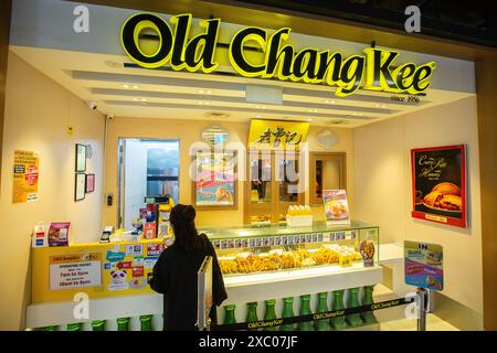 Eine Frau bezahlt an einem Old Chang Kee Establishment Outlet Kiosks, Snacks sind zum Mitnehmen. Singapur. Stockfoto