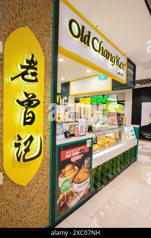 Vertikale Seitenansicht des Old Chang Kee Outlet mit chinesischen und englischen Schildern in einem Einkaufszentrum. Preis-Leistungs-Verhältnis: Gebäck-Snacks. Singapur. Stockfoto