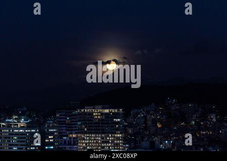 Luna llena brillante saliendo atras del volcan Cayambe en Quito Stockfoto