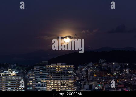 Luna llena brillante saliendo atras del volcan Cayambe en Quito Stockfoto