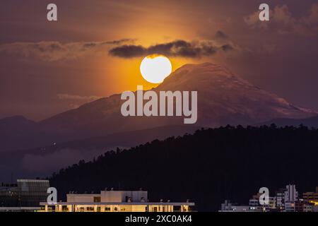 Luna llena brillante saliendo atras del volcan Cayambe en Quito Stockfoto