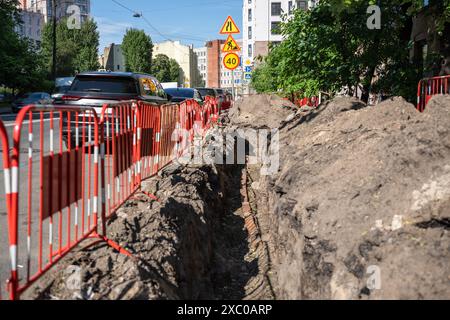 Graben für die Verlegung von elektrischen Kabeln in Stadtstraßen, Versorgungsarbeiten für den Austausch von Rohrleitungen. Stockfoto
