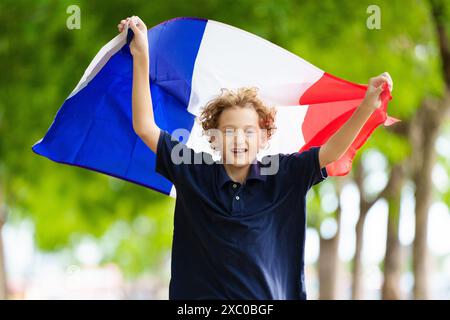 Kind mit laufender französischer Flagge. Ein Kind, das Frankreich anfeuert. Französischer Sportfan mit Nationalflagge. Happy Bastille Day. Aufgeregter Junge, der feiert Stockfoto