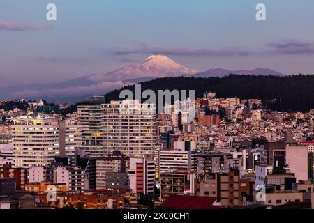 Edificios de Quito iluminados con el volcan Cayambe al fondo al anoChecer. Stockfoto