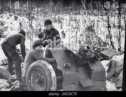 Screenshot des Zweiten Weltkriegs in Schwarzweiß. Eine deutsche leichte Infanterie-Kanone wird von Soldaten der deutschen Wehrmacht geladen. Stockfoto