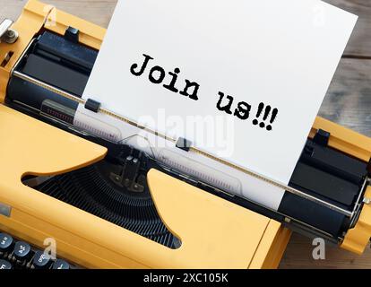 Wir stellen eine Kampagne zur Rekrutierung mit einer gelben Schreibmaschine vor, die „Join US“ zeigt Stockfoto