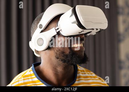 Afroamerikaner, der ein Virtual-Reality-Headset trägt, lächelnd Stockfoto