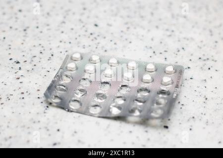 Eine Blisterpackung mit Pillen wird auf eine silberne Ablagefläche gelegt, um einen Kontrast der Materialien zu erzeugen. Die Nahaufnahme hebt das Muster und die Textur von Th hervor Stockfoto