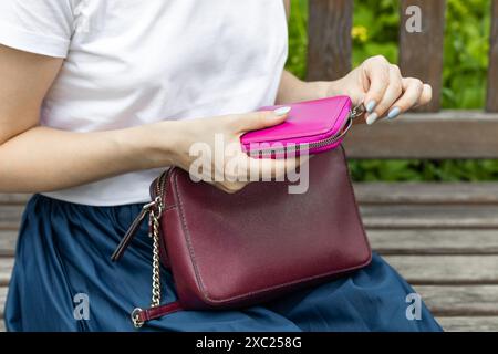 Frau öffnet den Reißverschluss an der Brieftasche, Nahaufnahme. Die Hand der Frau öffnet den Reißverschluss einer Brieftasche. Nahaufnahme. Stockfoto