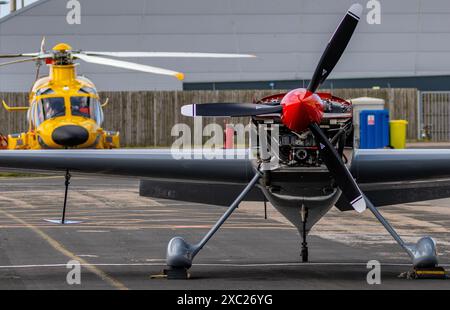 Kunstflugzeug mit roter Nase parkt vor einem gelben Hubschrauber Stockfoto