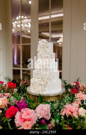 Weiße Hochzeitstorte mit Blumen aus Glasur und bunten Blumenstrauß Stockfoto