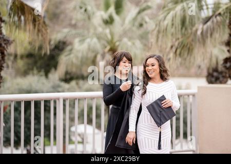 Mom trägt ein Abschlusskleid auf Tochter und lacht beide Stockfoto