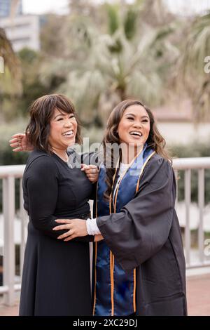Mom und Tochter lachen zusammen, während sie Abschlusskleid tragen Stockfoto