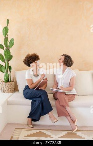 Zwei Profi-Frauen sitzen lachend auf der Couch Stockfoto