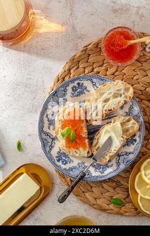 Sandwich mit Butter und rotem Kaviar auf einem Teller, Tee in einer Tasse und Stockfoto