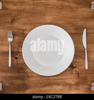 Leeren Teller mit Messer und Gabel auf hölzernen Hintergrund Stockfoto