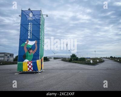 Euro 2024, Fußball-Europameisterschaft 2024, München, Fußball-Arena, Stadion, UEFA, große Werbetafel, bunte Grafiken, öffentliche Veranstaltung, sportliches Ereignis, festliche Stimmung, Vorbereitungen, modernes Design, Windrad, bewölkter Himmel, Infrastruktur *** Euro 2024, Fußball-Europameisterschaft 2024, München, Fußballarena, Stadion, UEFA, große Plakatwand, bunte Grafiken, öffentliche Veranstaltung, Sportveranstaltung, festliche Atmosphäre, Vorbereitungen, modernes Design, Windkraftanlage, bewölkter Himmel, Infrastruktur Copyright: xGrantxHubbsx Stockfoto