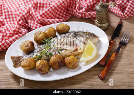Teller mit gebackenem Fisch mit Kartoffeln auf Holztisch Stockfoto