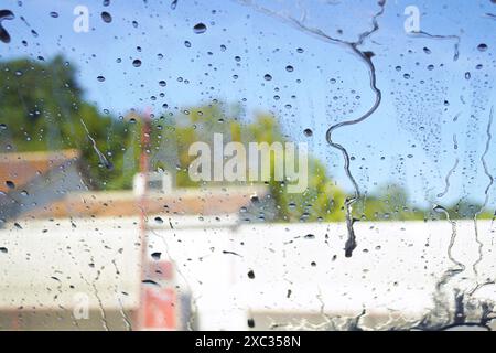 Seifenflecken fließen an der Windschutzscheibe des Autos entlang. Foto aus dem Auto, aufgenommen in einer Autowaschanlage. Stockfoto