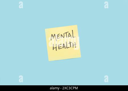 Psychische Gesundheit geschrieben auf einem gelben Klebepapier auf blauem Hintergrund Stockfoto