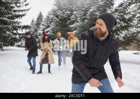 Junge glückliche, fröhliche Menschen, die Schneeballschlacht im verschneiten Winterpark genießen und gemeinsam im Wald spazieren gehen. Stockfoto