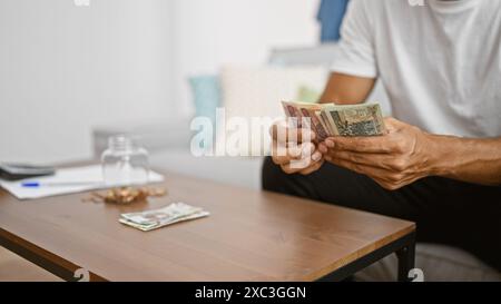 Junger hispanischer Mann, der zu Hause polnische Zloty-Scheine zählt Stockfoto