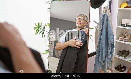 Ein reifer Mann probiert einen Anzug in einem gut organisierten Umkleideraum sorgfältig an, um Stil und Vorbereitung widerzuspiegeln. Stockfoto