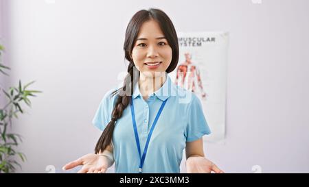 Eine junge asiatische Frau in medizinischer Kleidung steht in einer Klinik mit freundlichem Verhalten. Stockfoto