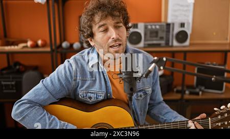 Hispanischer Mann singt und spielt Gitarre in einem Musikstudio Stockfoto