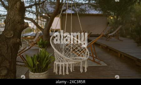 Ein ruhiges Ambiente im Freien mit einer rustikalen Holzterrasse mit hängenden Stühlen, umgeben von üppigem Grün und Bäumen, bietet eine ideale Atmosphäre für Stockfoto