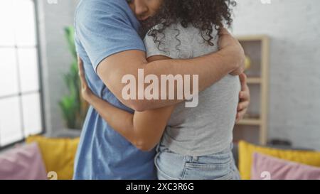 Ein liebevolles Paar umarmt sich herzlich in einem gemütlichen Wohnzimmer und zeigt Zuneigung und eine komfortable Atmosphäre. Stockfoto