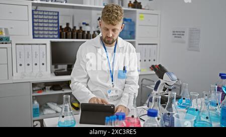 Kaukasischer Mann mit blauen Augen und Bart arbeitet im Labor, analysiert Daten auf Tablette in der medizinischen Klinik. Stockfoto