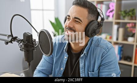 Hübscher hispanischer Mann mit lächelndem Bart im Radio-Studio Stockfoto