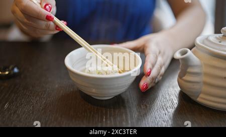 Moderner Lebensstil, junge kaukasische Frau genießt ihr gesundes japanisches Essen, isst Reis mit Essstäbchen in einem asiatischen Gourmetrestaurant Stockfoto