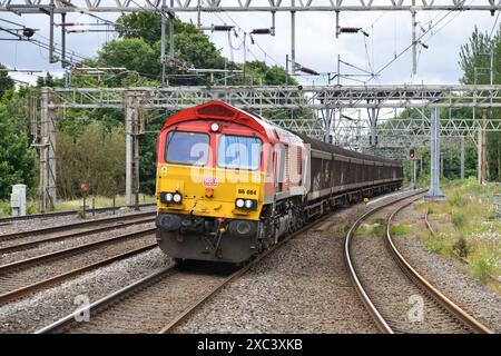 Die DB Cargo Red Class 66 66084 nähert sich dem Rugeley Trent Valley und arbeitet am 14. Juni 2024 mit 6M13 vom 01:04 Dollands Moor zur Ditton Foundry. Stockfoto