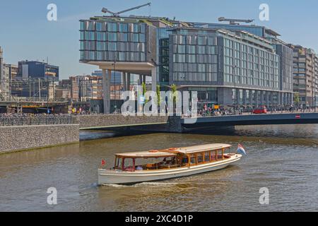 Amsterdam, Niederlande - 14. Mai 2018: Boot im Vintage-Stil vor dem modernen New Double Tree by Hilton Hotel Building am zentralen Herbsttag der Stadt. Stockfoto