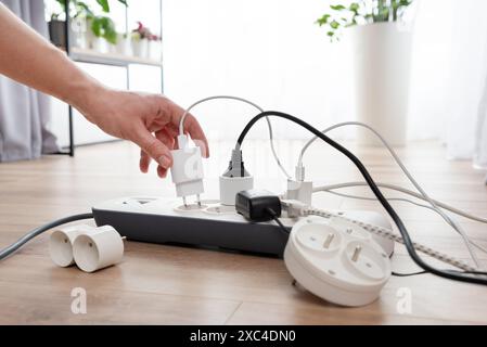 Mann, der den Netzstecker einsteckt. Steckdose zu Hause. Stockfoto