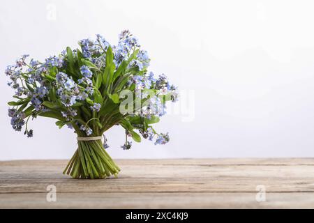 Blumenstrauß mit schönen Vergissmeinnicht-Blumen auf Holztisch vor weißem Hintergrund, Platz für Text Stockfoto