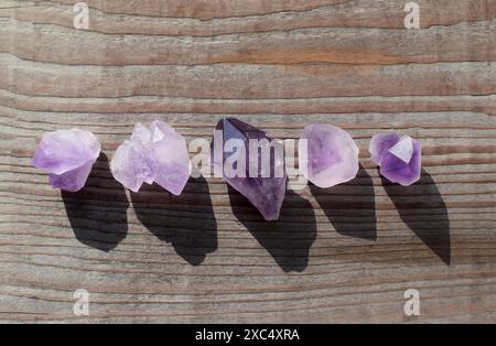 Wunderschöne natürliche Amethyst-Kristalle, beleuchtet durch Sonnenlicht auf einem alten hölzernen Hintergrund. Heilkristalle. Stockfoto