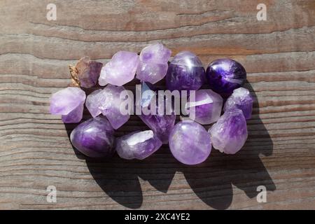 Wunderschöne natürliche Amethyst-Kristalle, beleuchtet durch Sonnenlicht auf einem alten hölzernen Hintergrund. Heilkristalle. Stockfoto