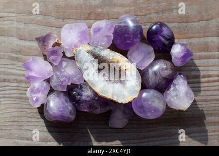 Wunderschöne natürliche Amethyst-Kristalle und Geode beleuchtet durch Sonnenlicht auf einem alten hölzernen Hintergrund. Heilkristalle. Stockfoto