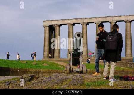 Besucher auf Carlton Hill bei der alten portugiesischen Kanone mit unvollendetem Nationaldenkmal im Hintergrund.Edinburgh.Schottland.Vereinigtes Königreich Stockfoto