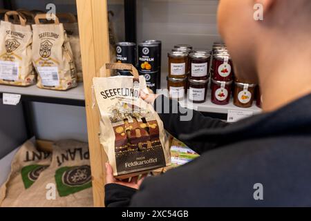 Bad Nauheim, Deutschland. Juni 2024. Eine Frau untersucht die angebotenen Kartoffeln. 2023 eröffnete Hoffreunde den Selbstbedienungs-Hoflagercontainer in Bad Nauheim, zusätzlich zum regulären Hofladen Hoffreunde in Butzbach. Kunden können hier rund um die Uhr mit ihrer EC-Karte einkaufen. Kunden finden eine Auswahl regionaler Lebensmittel, die am Ende des Kaufs über das Selbstkassensystem bezahlt werden können. Quelle: Christian Lademann/dpa/Alamy Live News Stockfoto