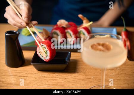 Eine Frau taucht köstliches Sushi in die Schüssel mit der Sojasauce Stockfoto